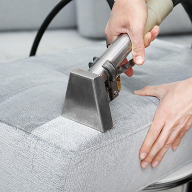 Dry cleaner's employee removing dirt from furniture in flat, closeup